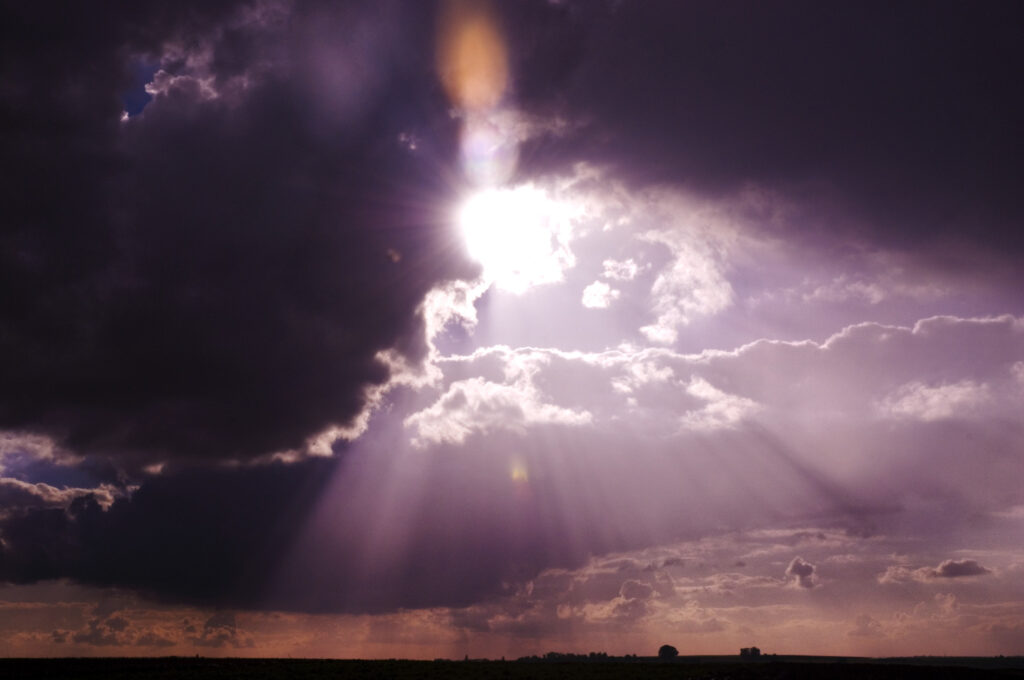 Sinn-Bild #507 The purple drama queen | Himmelausschnitt, viele leuchtenden Sonnenstrahlen durchbrechen die dunkeln Wolken, lila schimmernd. (Bild von Adventuria® – Social Network & Journaling-Plattform, mit einem Tagebuch-Tool, einer unterstützenden Gemeinschaft und psychologischen Ratschlägen durch Podcasts)