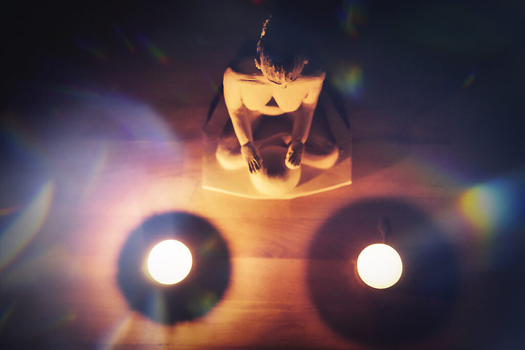Sinn-Bild #557 Vom Loslassen | Frauenkörper auf dem Boden sitzend, davor zwei leuchtende runde Gegenstände umgeben von dunklen Schatten. (Bild von Adventuria® – Social Network & Tagebuch-Software, für digitales Journaling, innerhalb einer unterstützenden Gemeinschaft und psychologischer Unterstützung durch Podcasts)